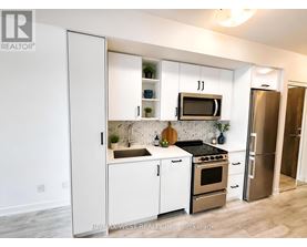 A kitchen with white cabinets and appliances, a sink, and a refrigerator.