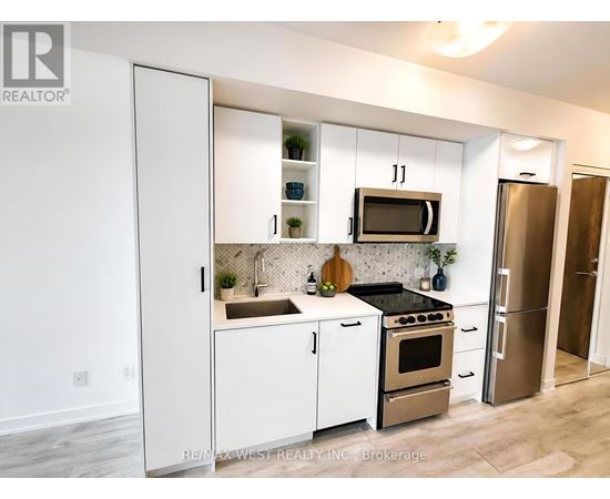 A kitchen with white cabinets and appliances, a sink, and a refrigerator.