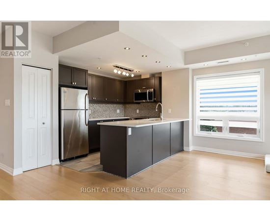 A modern kitchen with a refrigerator, microwave, and cabinets.