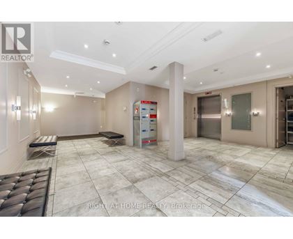 A spacious, well-lit room with a marble floor and a large white pillar in the center.