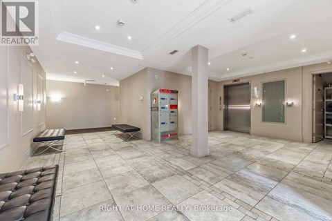 A spacious, well-lit room with a marble floor and a large white pillar in the center.