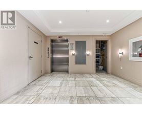 A spacious hallway with a tiled floor and a stainless steel elevator.
