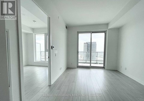 A spacious, empty room with a sliding glass door leading to a balcony.