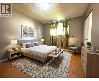A bedroom with a large bed, a chair, and a painting on the wall.