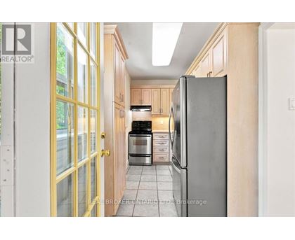 A kitchen with a refrigerator, oven, and cabinets.