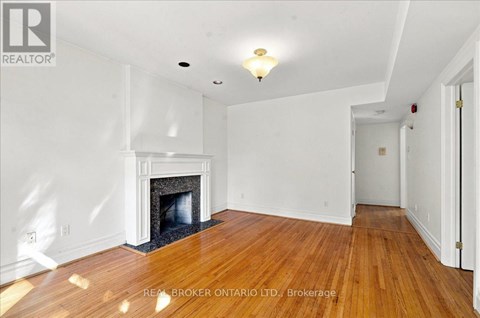 A spacious room with a fireplace and wooden floors.