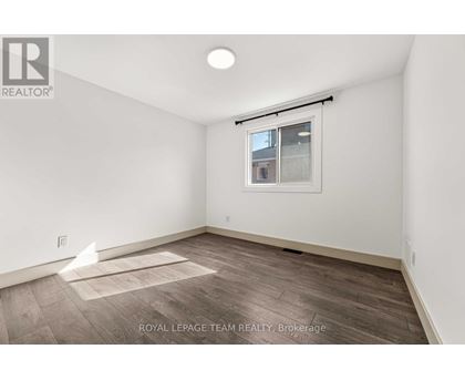 A white room with a window and a wooden floor.