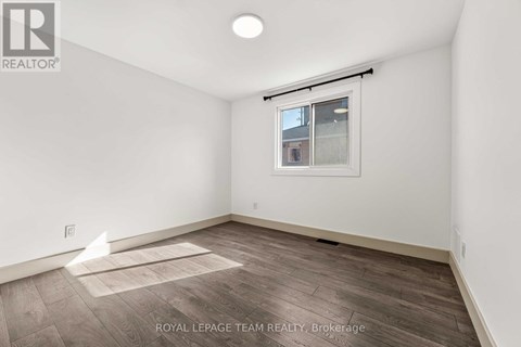 A white room with a window and a wooden floor.
