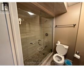 A bathroom with a toilet, a glass shower stall, and a towel bar.