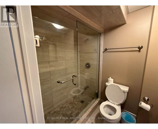 A bathroom with a toilet, a glass shower stall, and a towel bar.