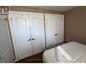 Three white doors are in a room with a bed.