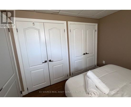 Three white doors are in a room with a bed.