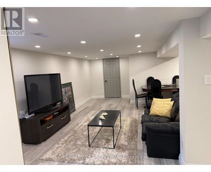A modern living room with a flat screen TV and a black couch.