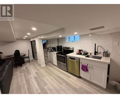 A modern kitchen with white cabinets and a wooden floor.