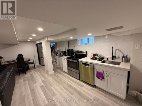 A modern kitchen with white cabinets and a wooden floor.