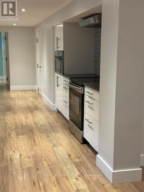 A modern kitchen with wooden floors and white cabinets.