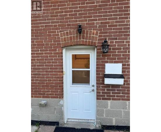 A white door with a glass window is set in a brick wall.