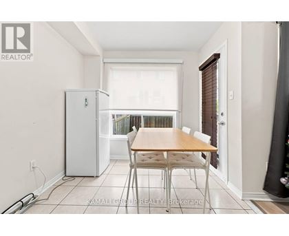A dining room with a table and chairs and a refrigerator.