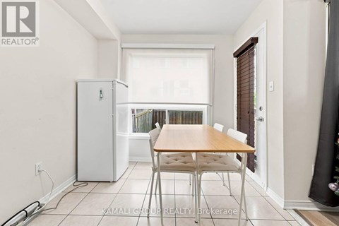 A dining room with a table and chairs and a refrigerator.