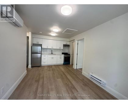 A kitchen with white cabinets and a wooden floor.