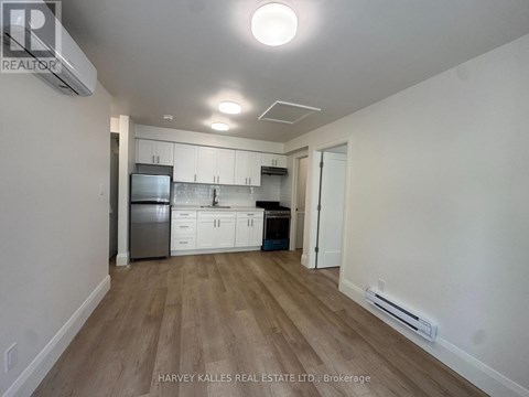 A kitchen with white cabinets and a wooden floor.