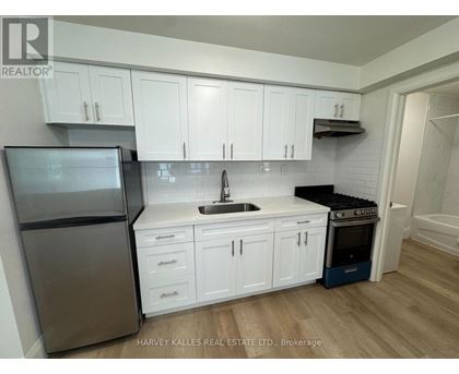 A kitchen with white cabinets and a stainless steel refrigerator.