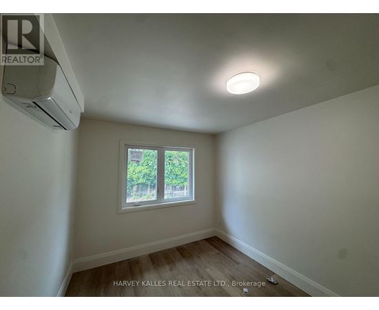 A room with a window and an air conditioner mounted on the wall.