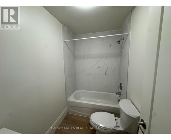 A white toilet sits next to a bathtub in a small bathroom.