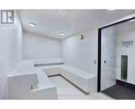 A white tiled bathroom with a glass door leading to a shower.