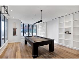 A billiard table is in the middle of a room with wood floors and white walls.
