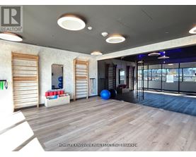 A spacious room with wooden floors and a large window with blinds.