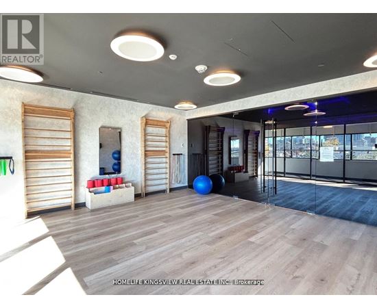A spacious room with wooden floors and a large window with blinds.