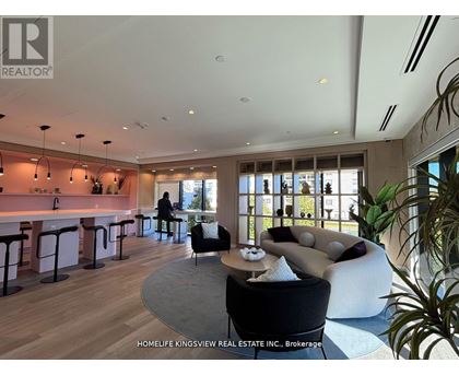A modern living room with a kitchen area in the background.