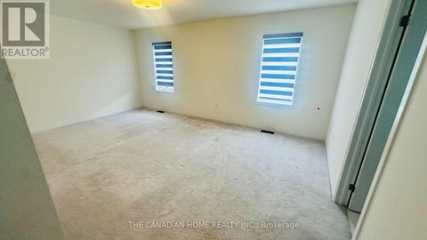 A room with a carpeted floor and two windows with blinds.