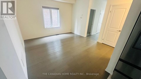 A spacious room with wooden flooring and white walls.