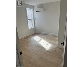 A room with light wood flooring and a window letting in sunlight.