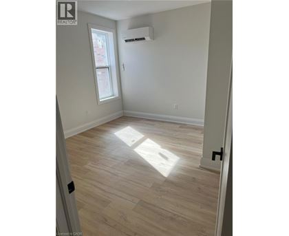 A room with light wood flooring and a window letting in sunlight.