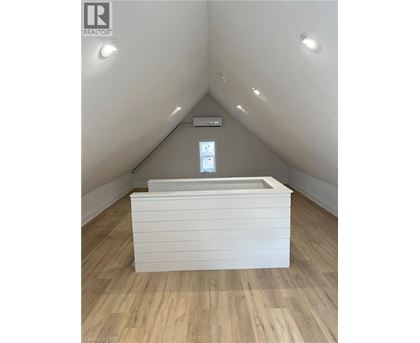 A white box with a window in the middle is on a wooden floor.