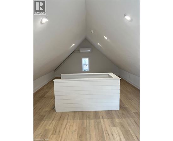 A white box with a window in the middle is on a wooden floor.