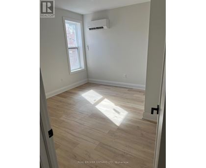 A room with light wood flooring and a window letting in sunlight.