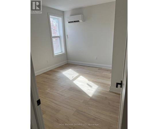 A room with light wood flooring and a window letting in sunlight.