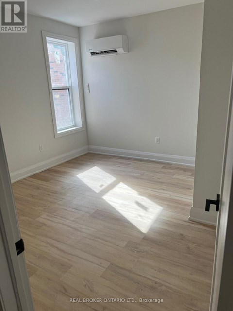 A room with light wood flooring and a window letting in sunlight.