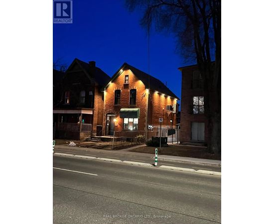 A house with a lit up sign that says REAL BROKER ONTARIO LTD. Brokerage.