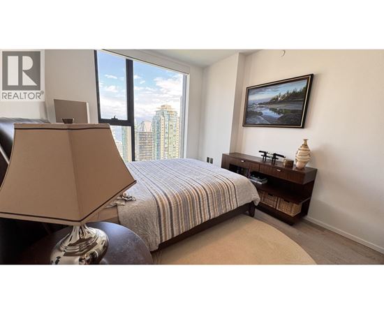 A bedroom with a bed, a lamp, and a painting on the wall.