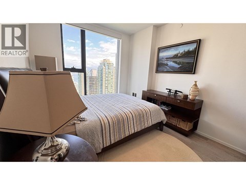 A bedroom with a bed, a lamp, and a painting on the wall.