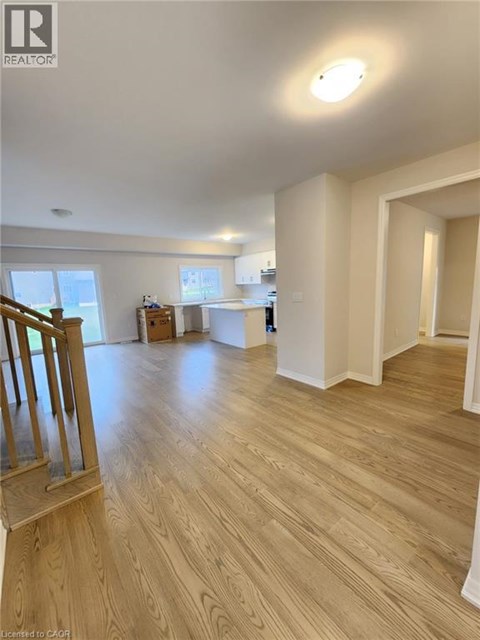 A spacious room with wooden flooring and white walls.
