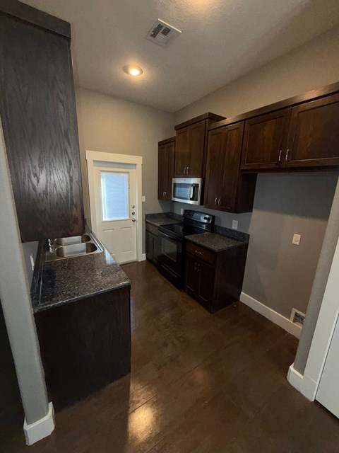 A kitchen with dark wood cabinets and a granite countertop.