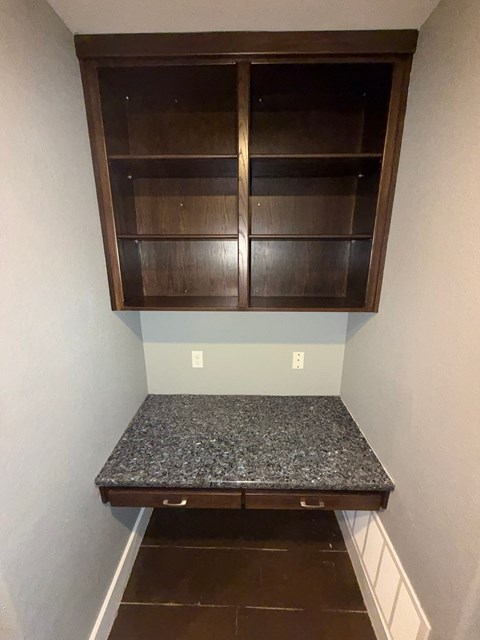 A corner cabinet with a granite countertop in a room.