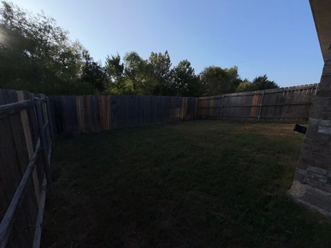 A backyard with a wooden fence and a grassy area.