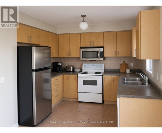 A kitchen with a black refrigerator, white stove, and wooden cabinets.